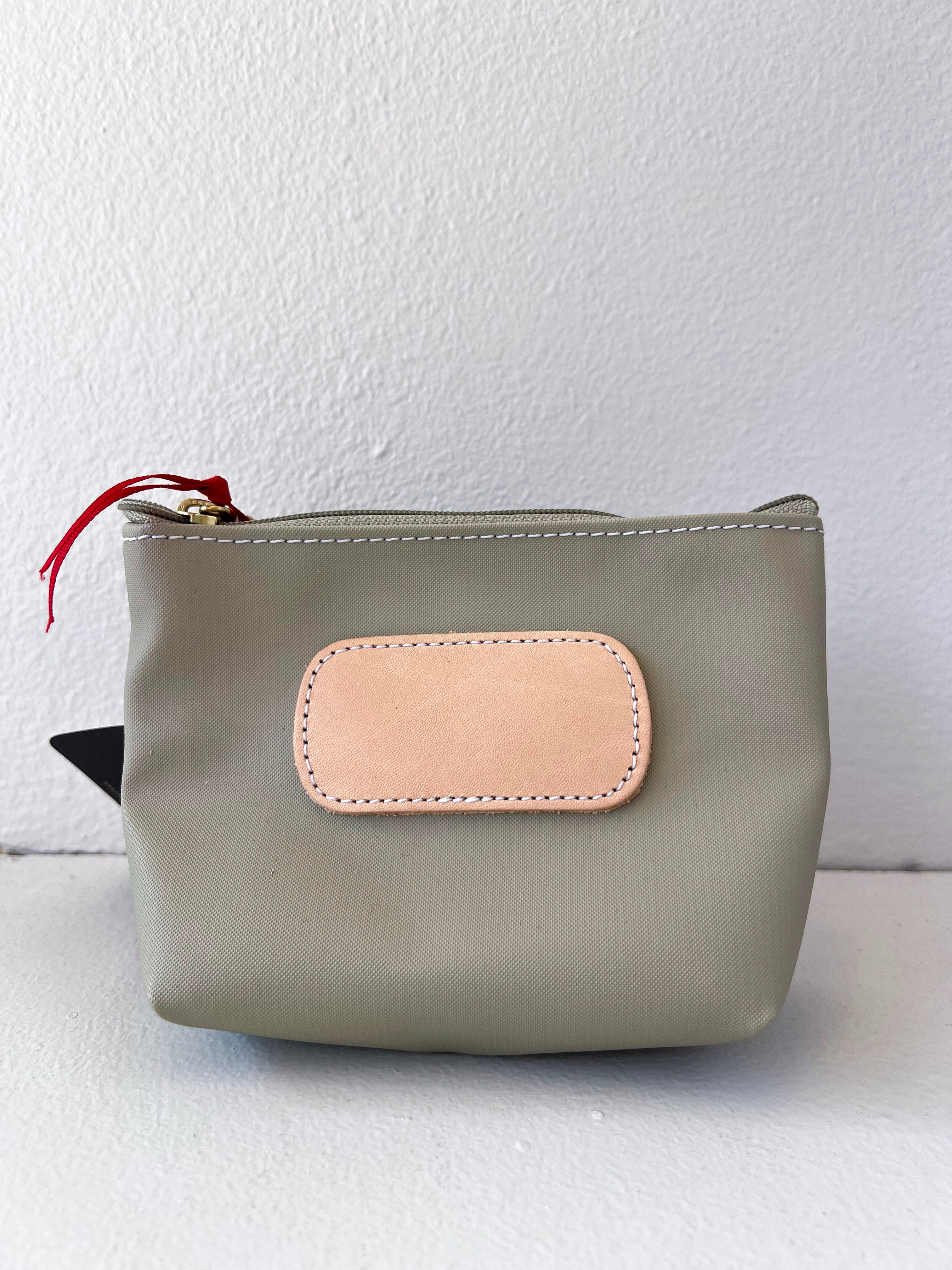 Gray pouch with a beige patch and red zipper pull on a white background