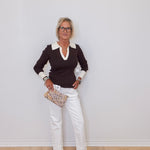 Woman wearing a black and white outfit with a clutch against a plain background