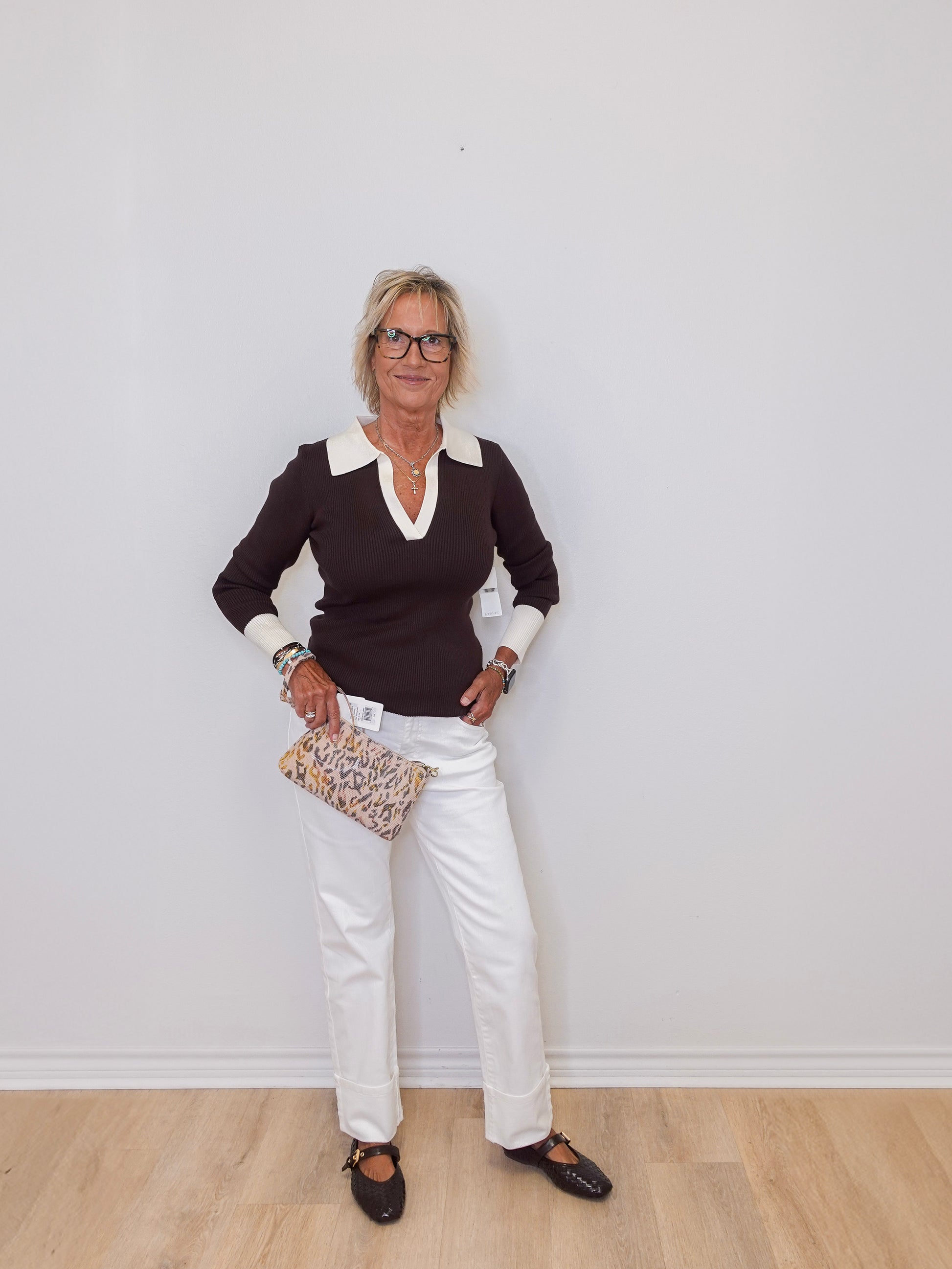 Woman wearing a black and white outfit with a clutch against a plain background