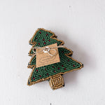 Green beaded tree-shaped ornament with a tag on a white background