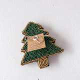 Green beaded tree-shaped ornament with a tag on a white background
