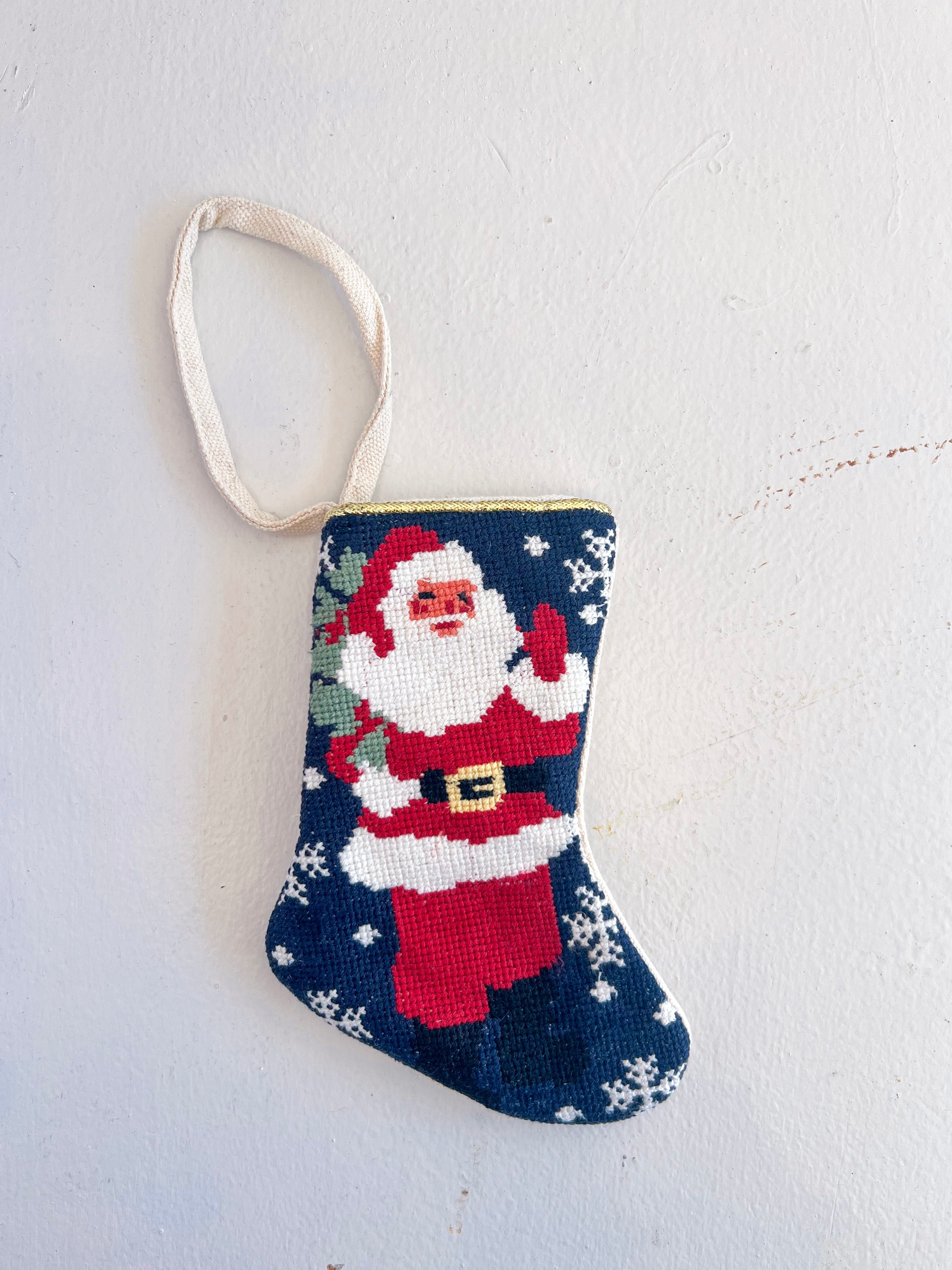 Small needlepoint Christmas stocking with Santa Claus on a white background