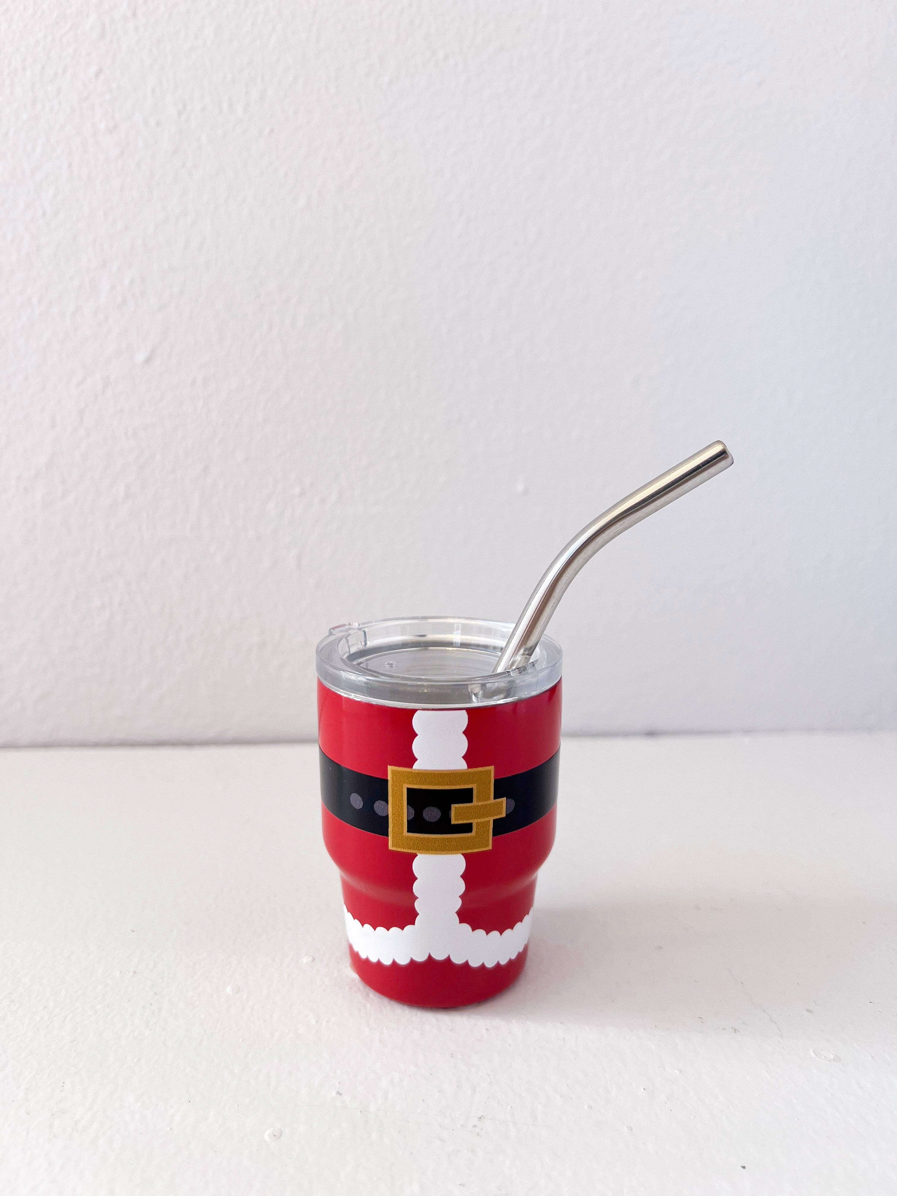 Red tumbler with Santa Claus design and metal straw on a white background