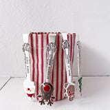 Set of Christmas-themed spoons with a striped container on a white surface.