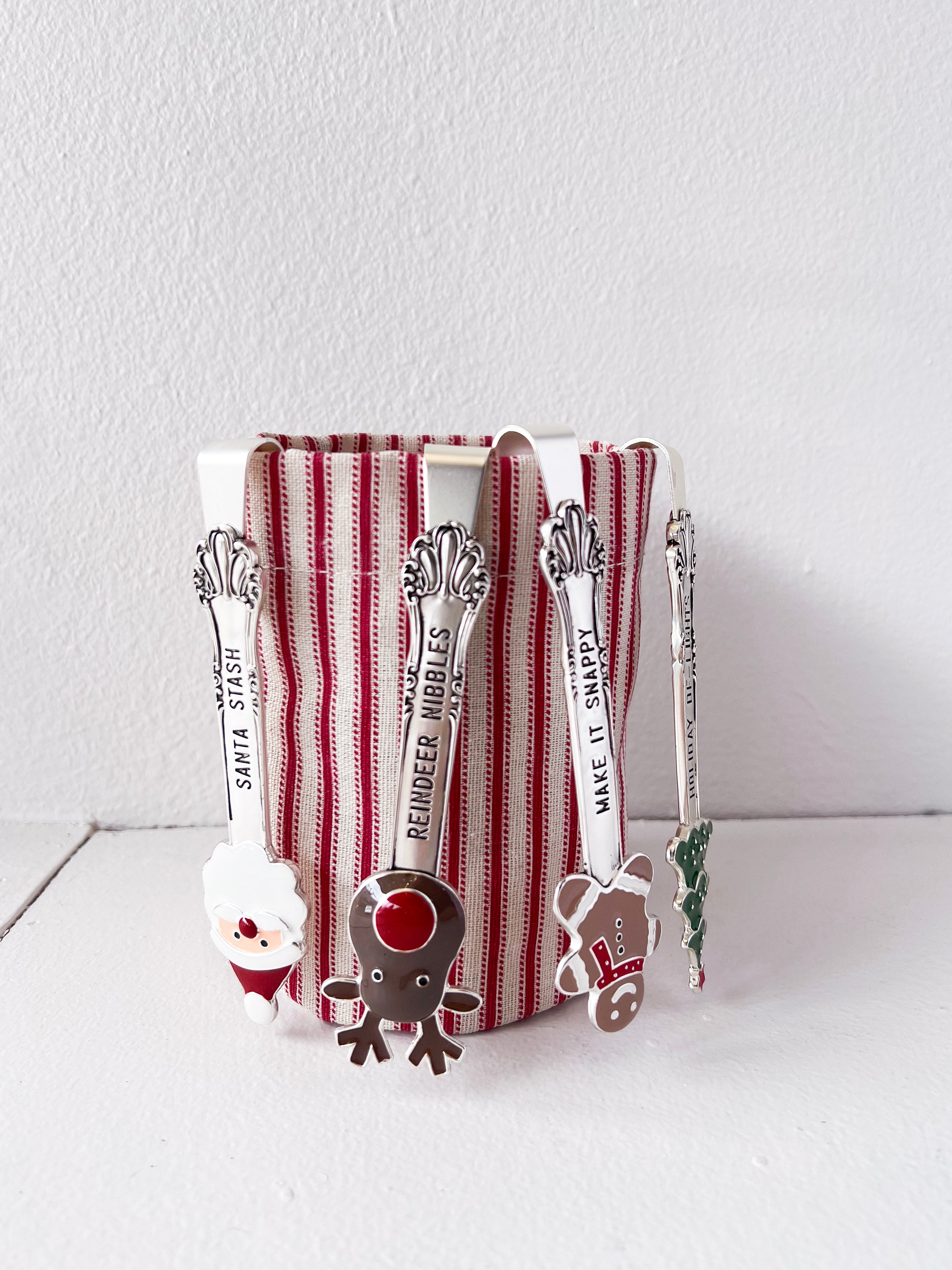 Set of Christmas-themed spoons with a striped container on a white surface.