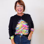 Woman wearing a black sweater with colorful sleeves against a white background