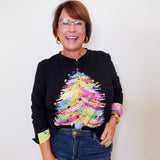 Woman wearing a black sweater with colorful sleeves against a white background