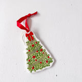 Christmas tree ornament with red berries and a red ribbon on a white background
