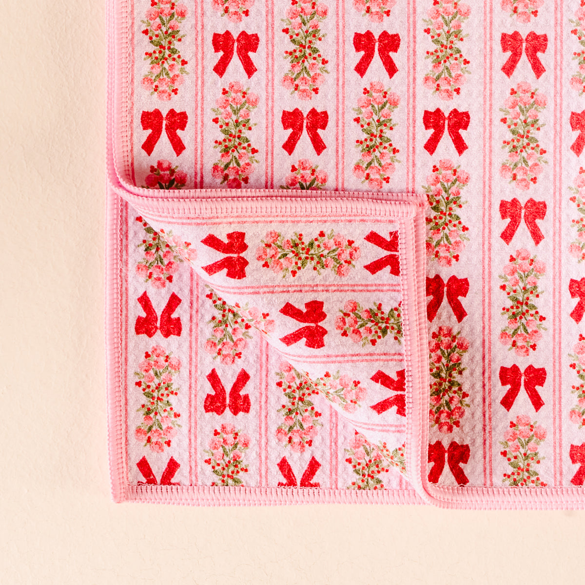 Pink fabric with red bow and floral pattern on a beige background