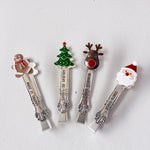 Four Christmas-themed spoons with decorative ends on a light gray background