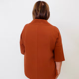 Person wearing a brown coat against a white background