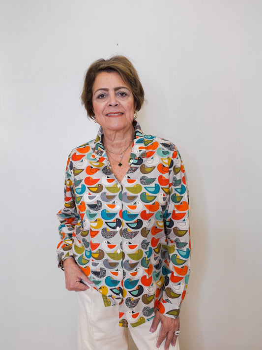 Woman wearing a colorful patterned shirt against a plain background
