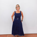 Woman wearing a navy blue dress with a belt against a white background