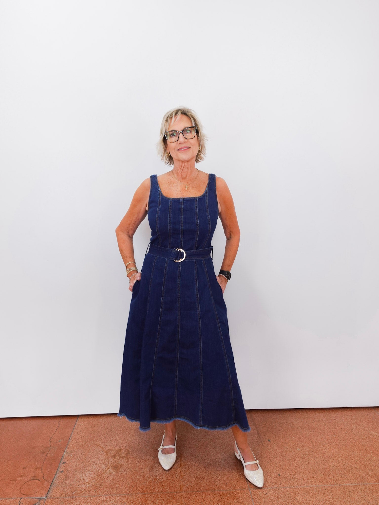 Woman wearing a navy blue dress with a belt against a white background