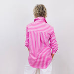 Person wearing a pink and white striped shirt against a plain background