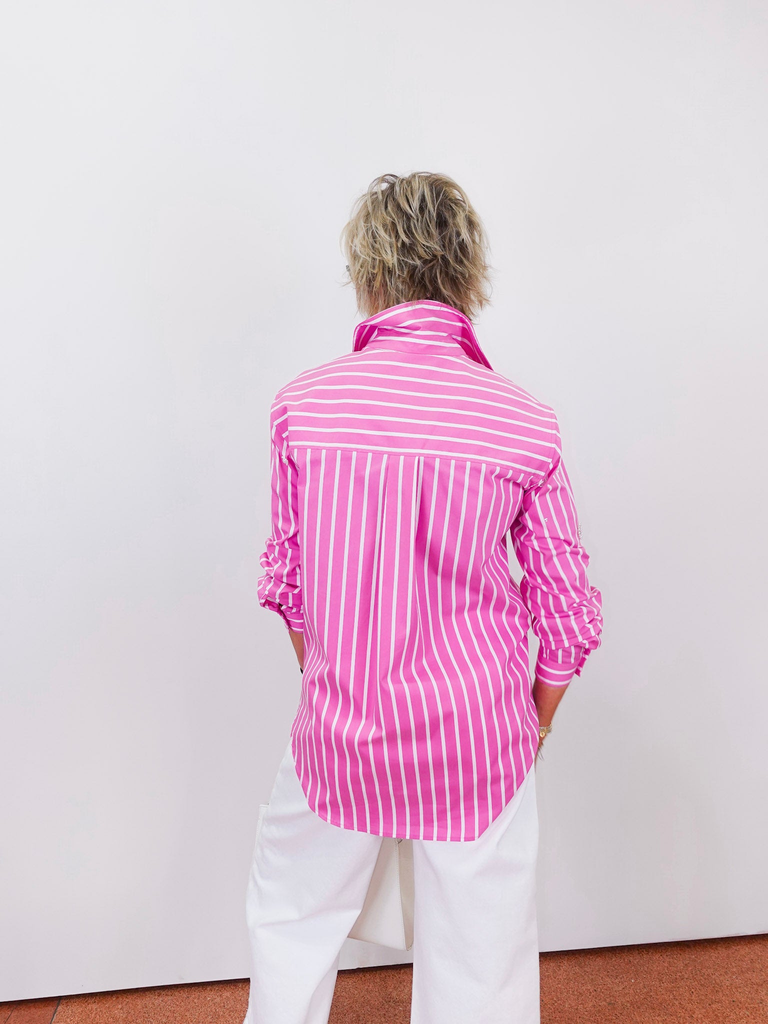 Person wearing a pink and white striped shirt against a plain background