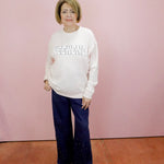 Person wearing a pink sweatshirt with 'Weekend' text and dark pants against a pink background