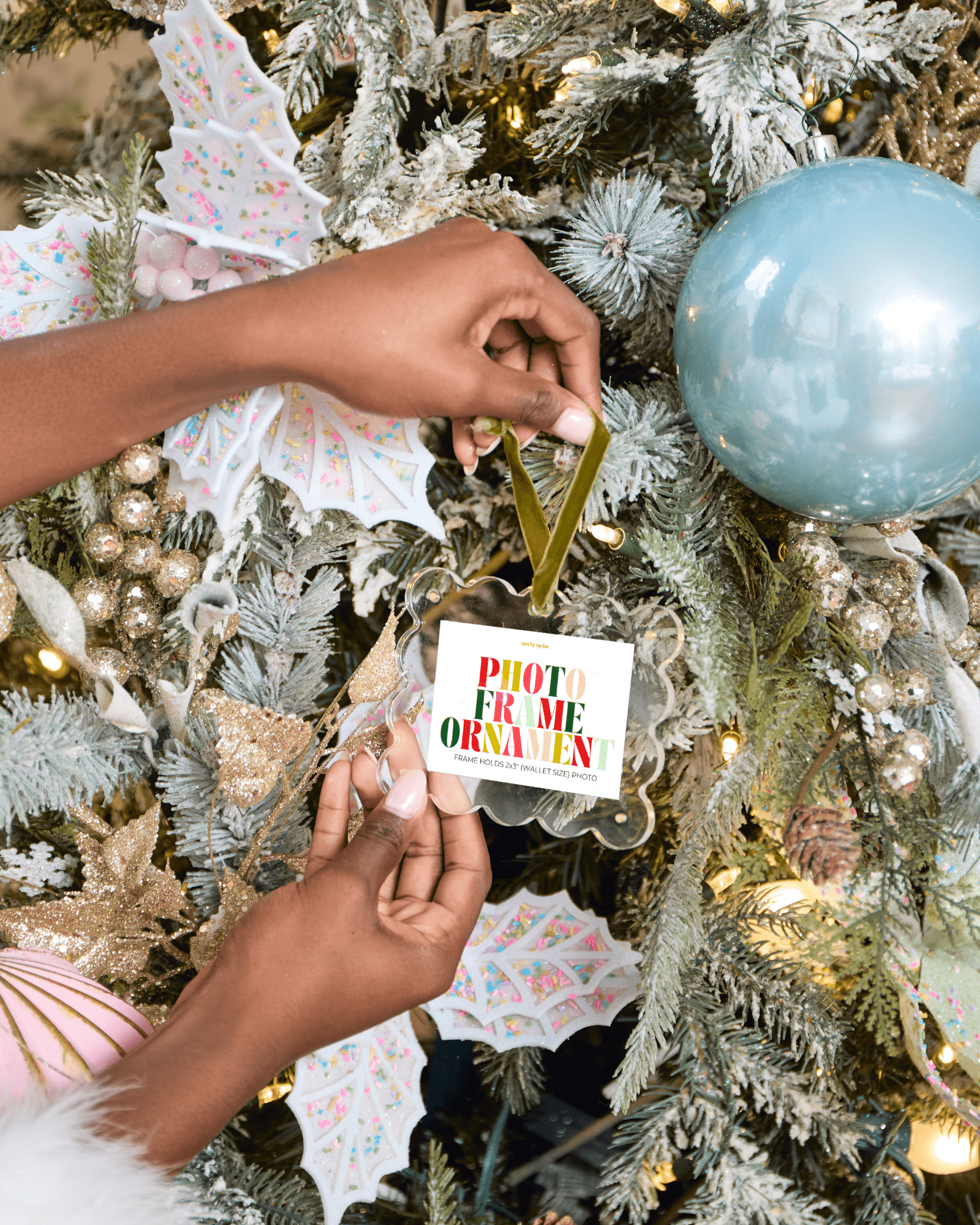Person decorating a Christmas tree with a 'Photo Frame Ornament' card.