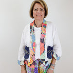 Woman wearing a colorful scarf and patterned outfit against a white background