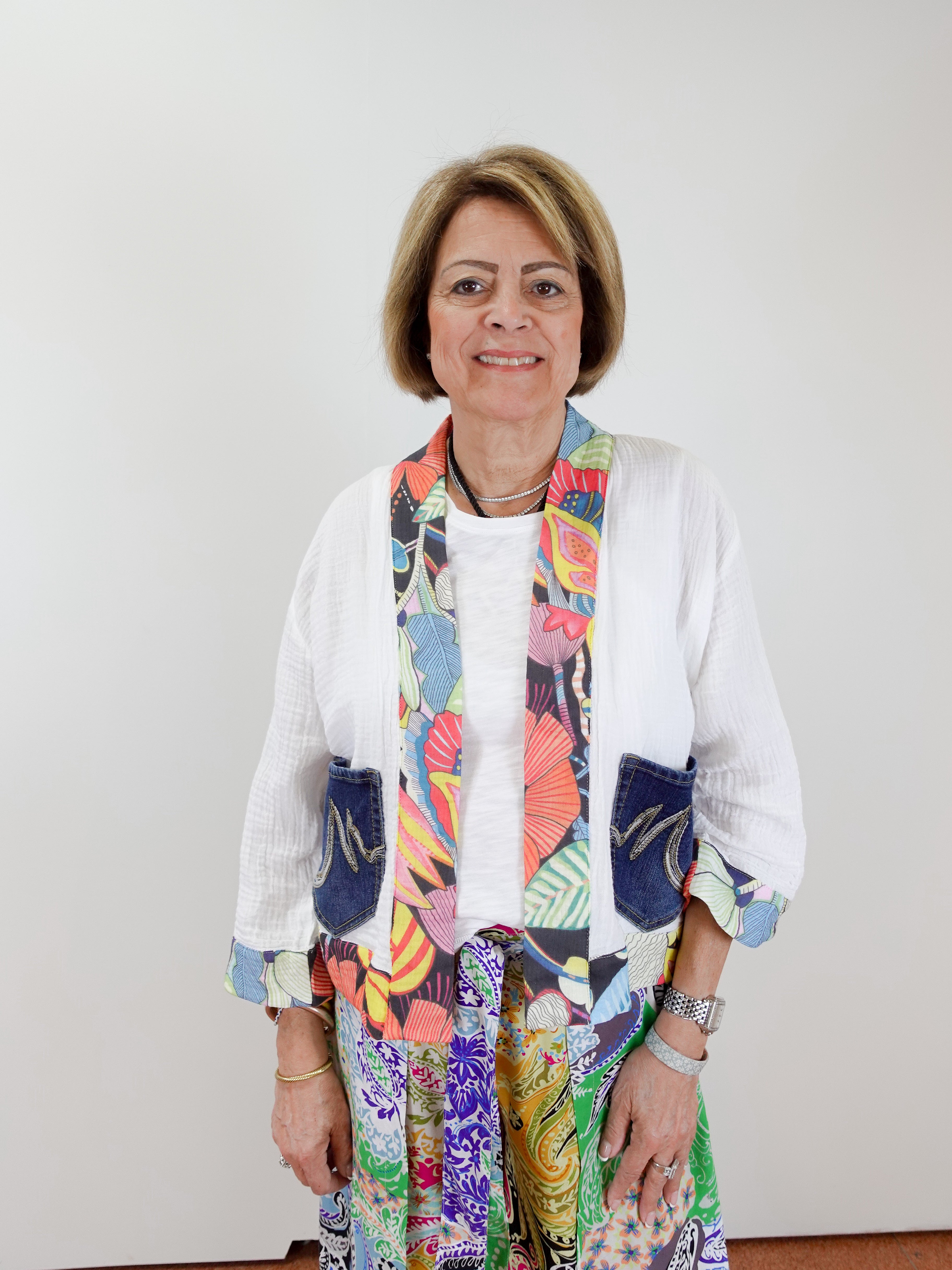 Woman wearing a colorful scarf and patterned outfit against a white background