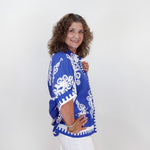 Woman wearing a blue and white patterned top against a white background