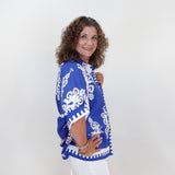 Woman wearing a blue and white patterned top against a white background
