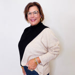 Woman wearing a black and beige sweater with a plain background