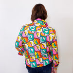 Person wearing a colorful apny patterned shirt against a white background