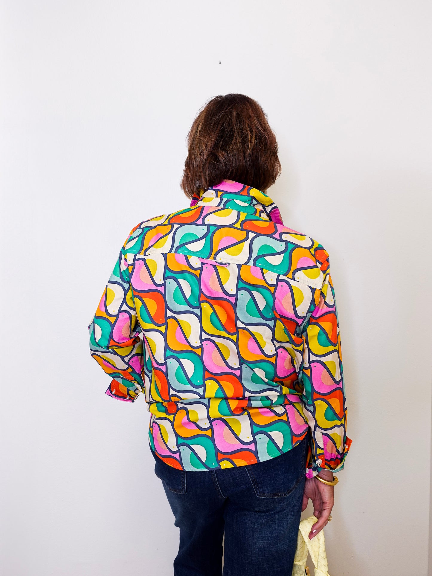 Person wearing a colorful apny patterned shirt against a white background