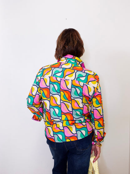 Person wearing a colorful apny patterned shirt against a white background