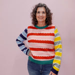 Woman wearing a colorful striped sweater against a plain background