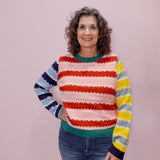 Woman wearing a colorful striped sweater against a plain background