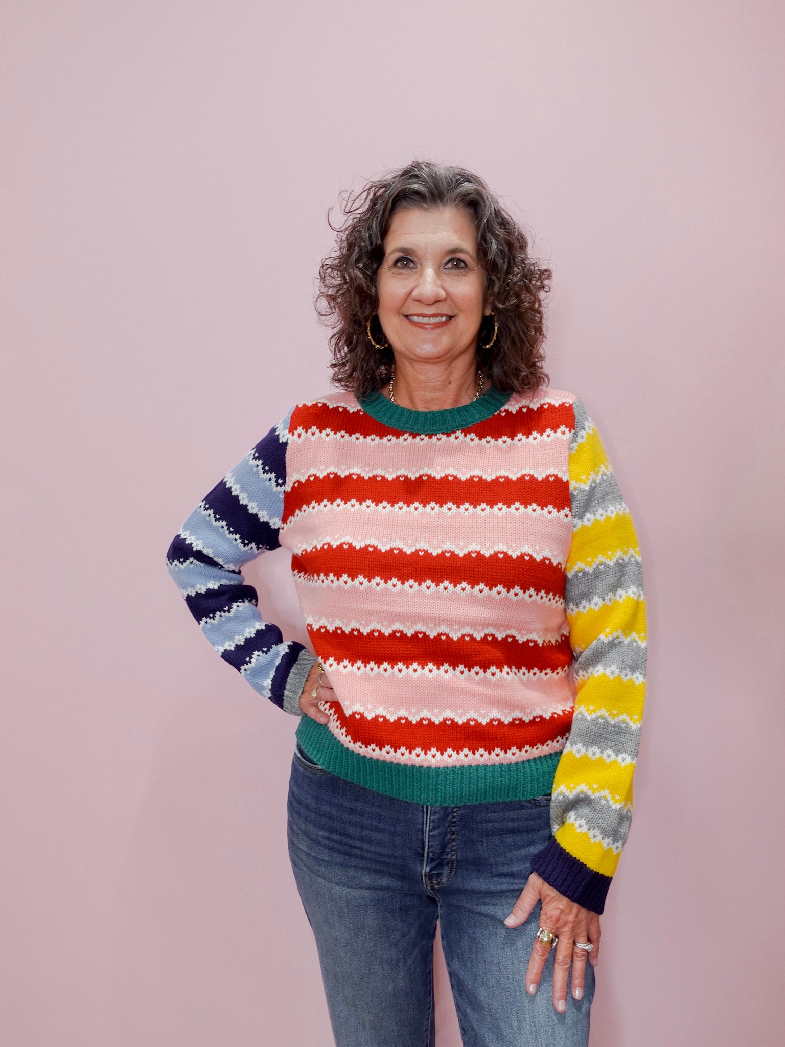Woman wearing a colorful striped sweater against a plain background