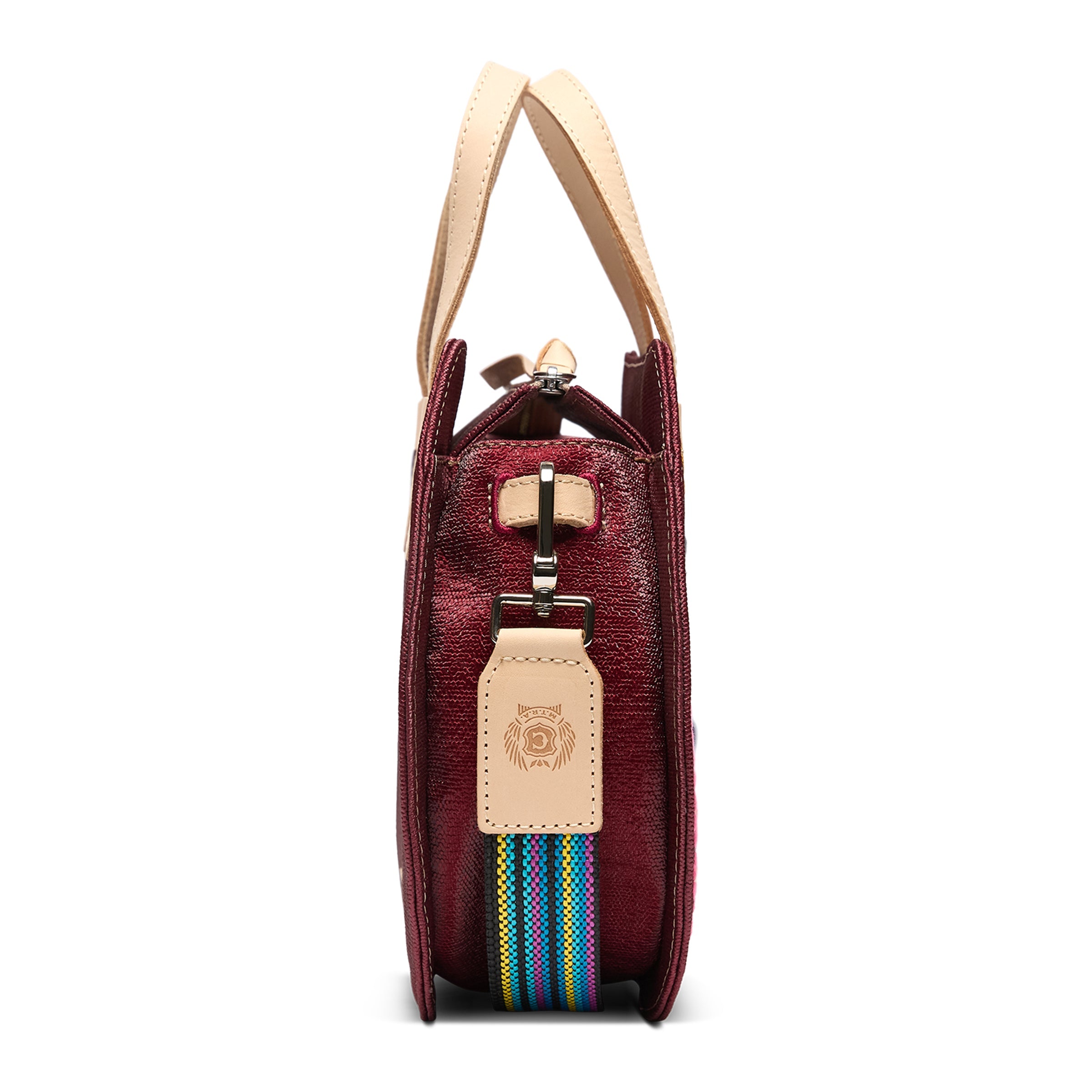 Maroon handbag with beige handle and colorful strap on a white background