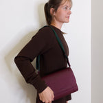 woman wearing consuela plum on the town crossbody-bag against a white background. 