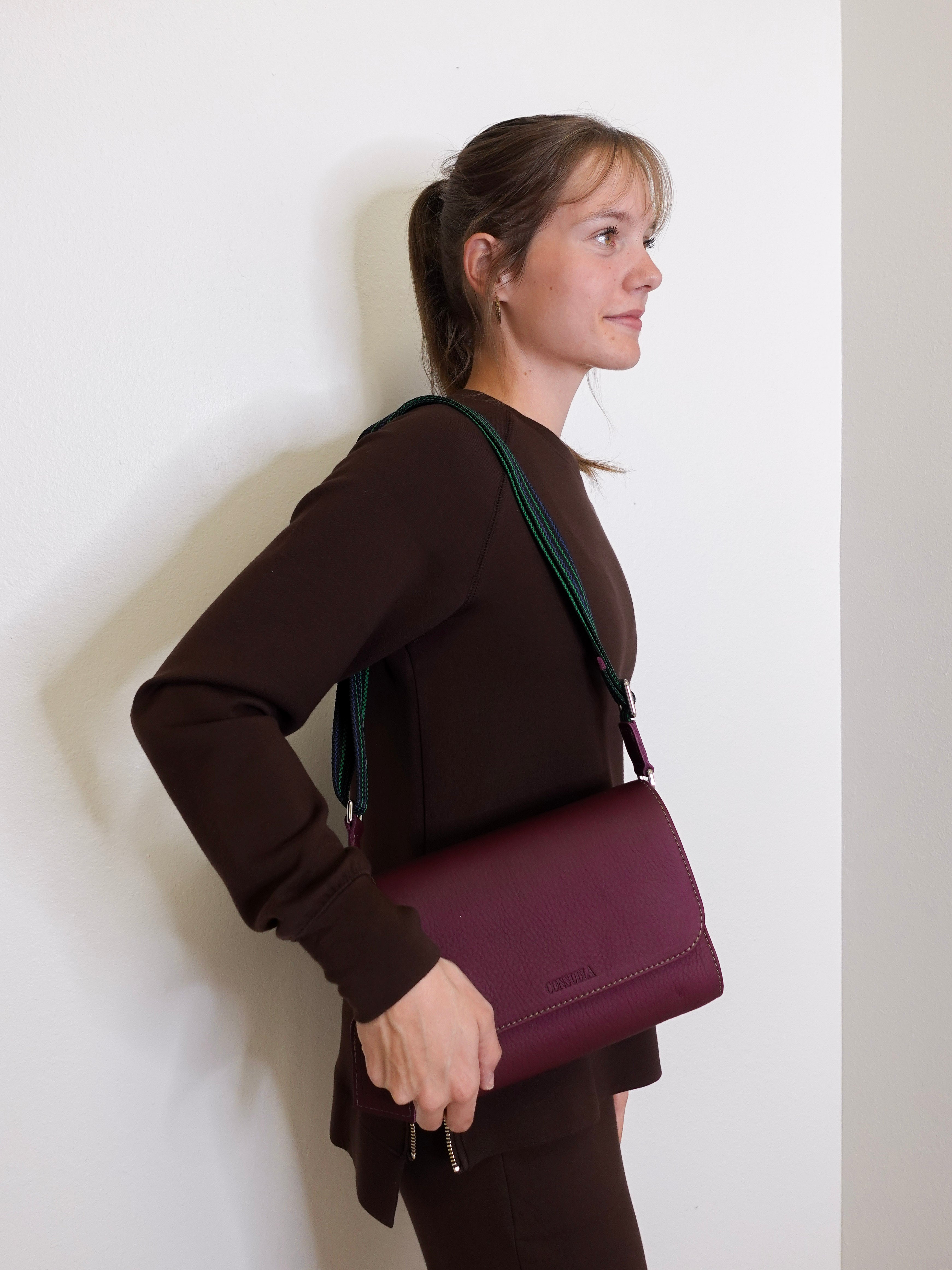 woman wearing consuela plum on the town crossbody-bag against a white background. 