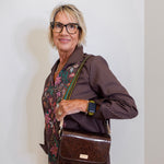 Woman holding a brown leather bag against a white wall