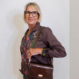 Woman holding a brown leather bag against a white wall