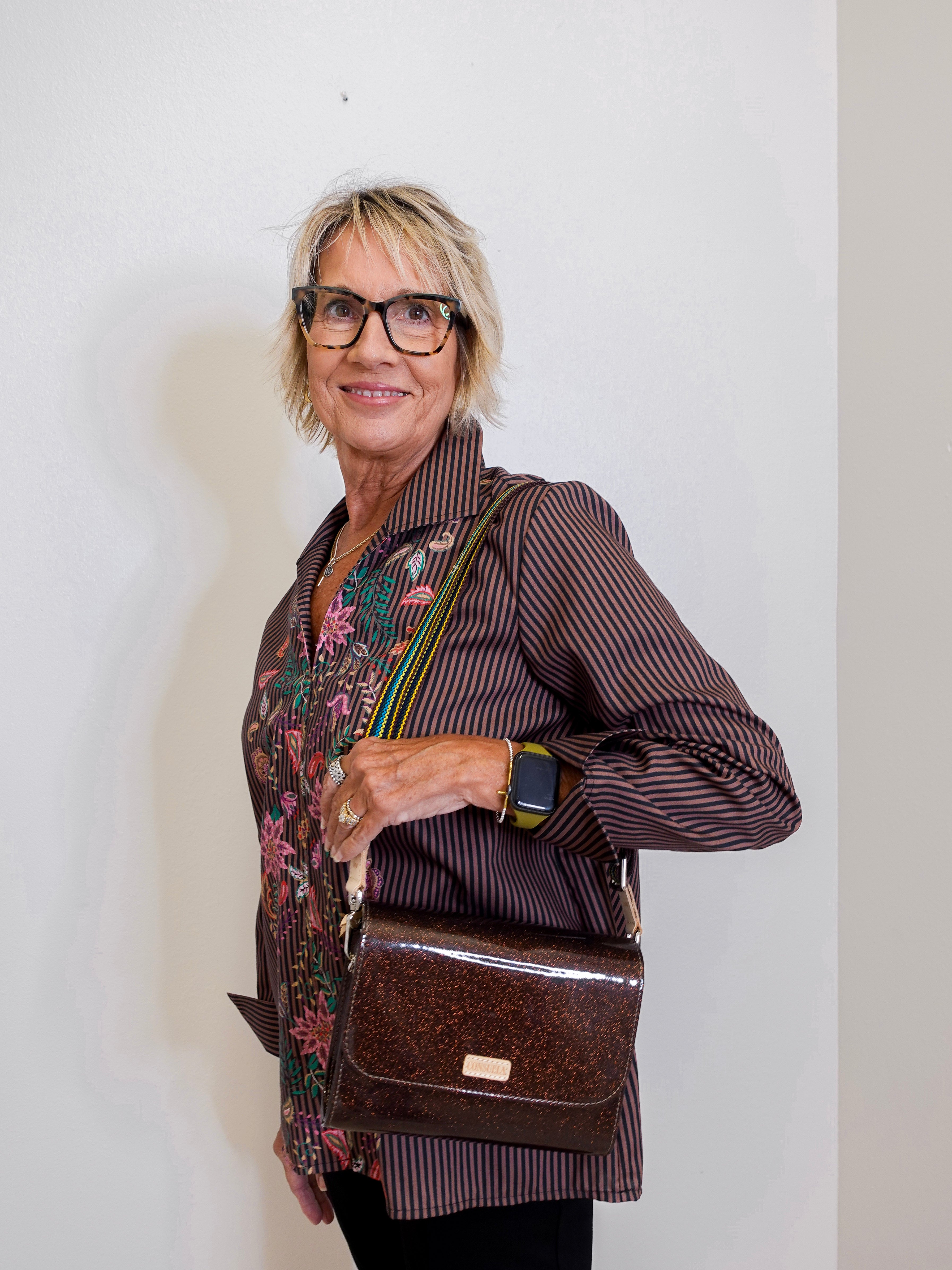 Woman holding a brown leather bag against a white wall