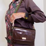 Person wearing a patterned shirt and holding a brown glittery handbag.
