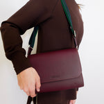 woman wearing consuela plum on the town crossbody-bag against a white background. 