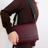woman wearing consuela plum on the town crossbody-bag against a white background. 