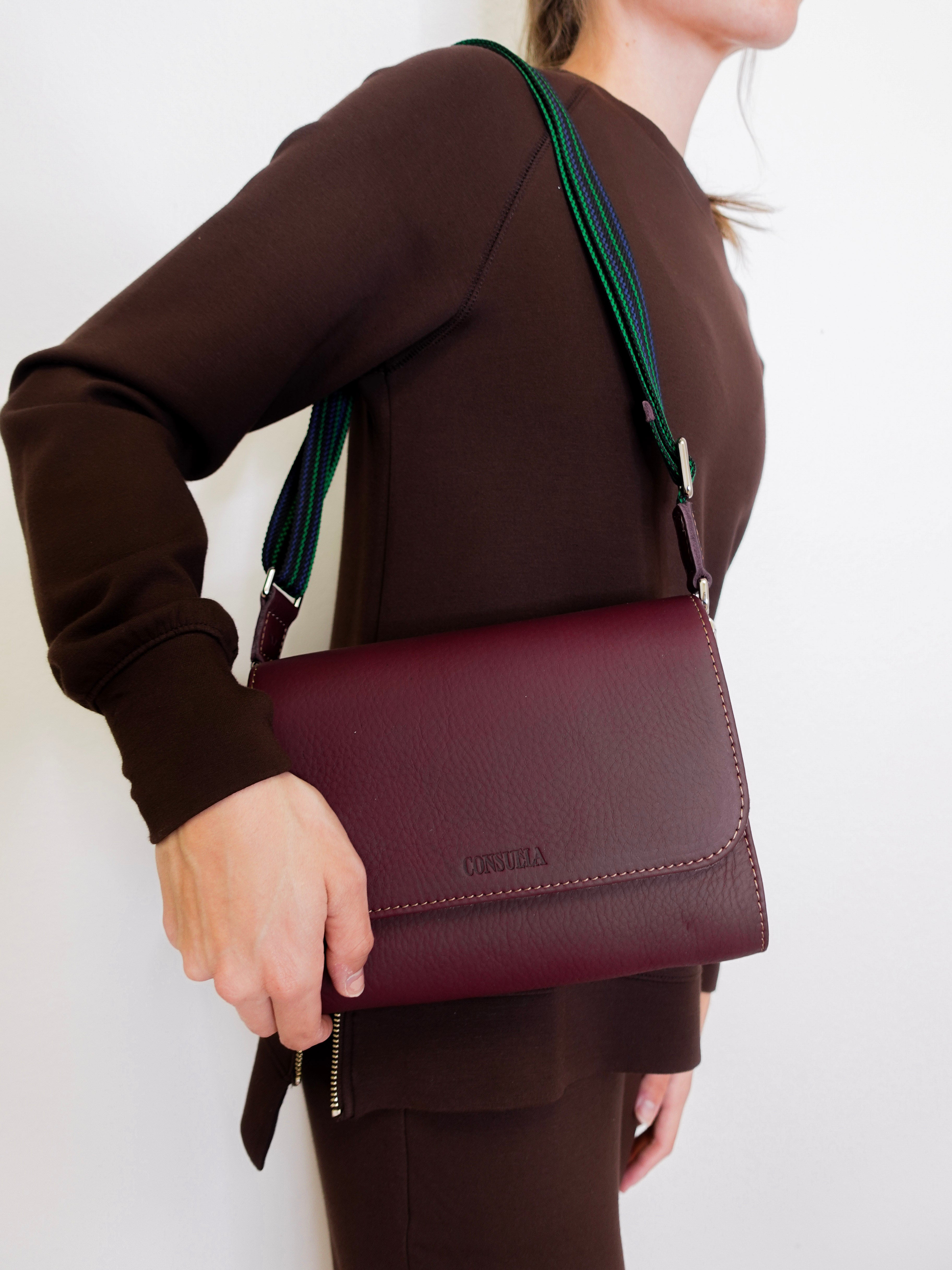 woman wearing consuela plum on the town crossbody-bag against a white background. 