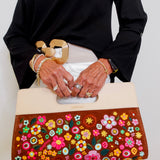 Person holding a handbag with floral design and gold accents