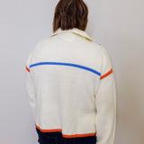 Person wearing a white sweater with colorful stripes on a plain background