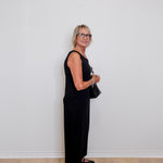 Woman in a black outfit standing against a white wall