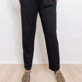 Person wearing black pants and leopard print shoes on a light wooden floor.