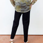 Person wearing a floral embroidered top and black pants on a plain background