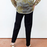 Person wearing a floral embroidered top and black pants on a plain background