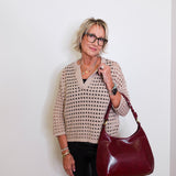 Woman holding a burgundy handbag against a white wall